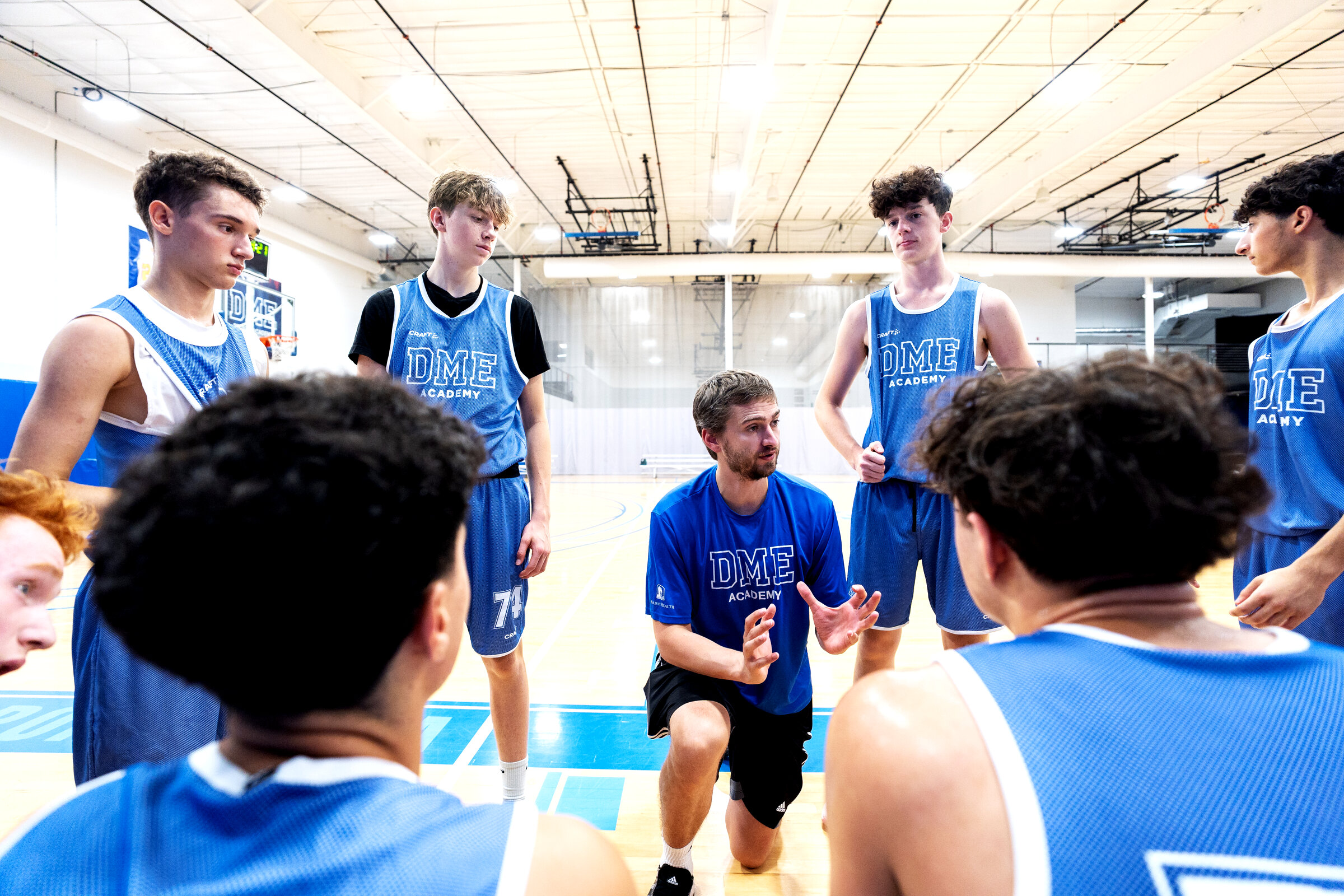 Basketball coach addressing player huddle in structured supervision
